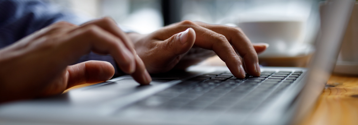 Close up of hands typing on computer keyboard panoramic banner